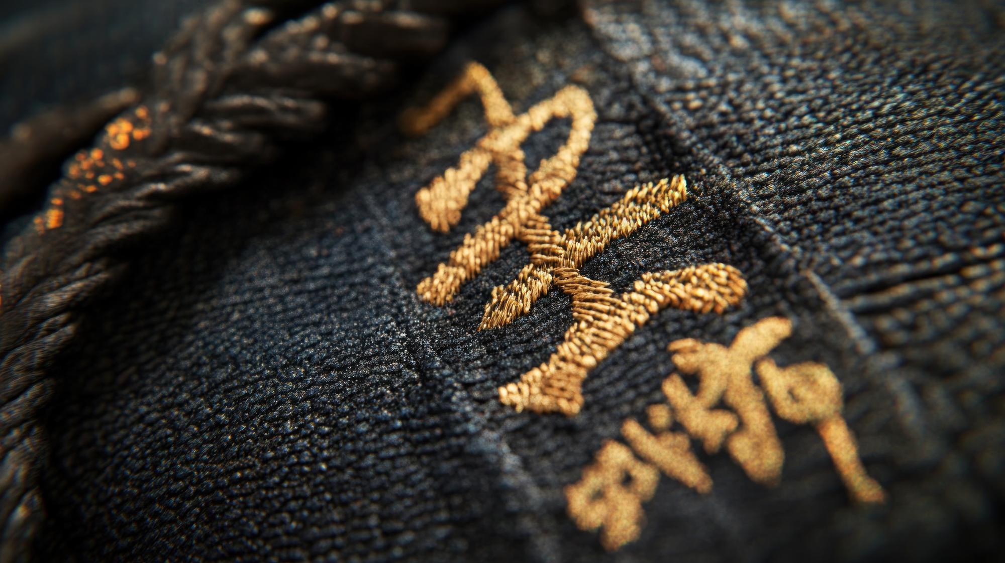 Close-up of gold thread hand embroidery on dark fabric